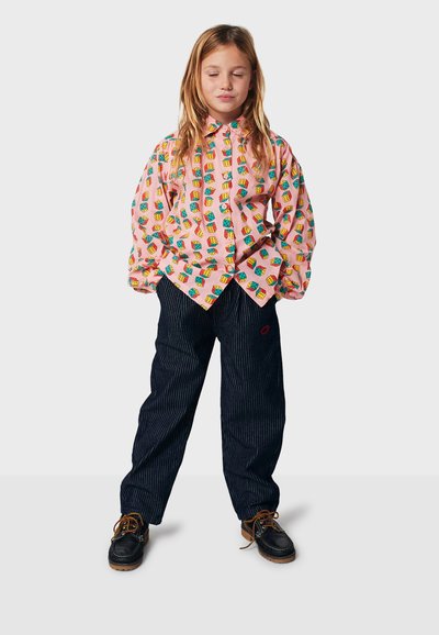 Colorful pink shirt with a house pattern, paired with dark striped pants. The shirt features a collar and button front, while shoes are dark with laces.