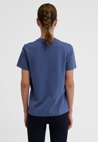 Kortärmad t-shirt med rund hals i en dämpad blå färg med en mjuk textur. Enkelt design utan synliga mönster eller detaljer.