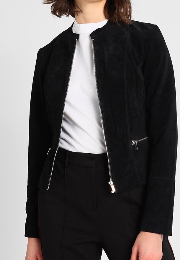 Černá semišová bunda na zip přes bílý tričko s kulatým výstřihem, k tomu černé kalhoty s vysokým pasem.