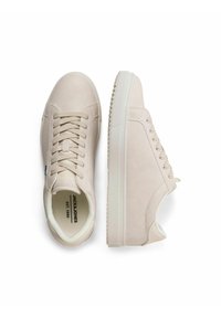 Sneakers beige con lacci, realizzati in materiale sintetico liscio e con collo imbottito, dotati di suola in gomma testurizzata e logo del marchio all'interno.