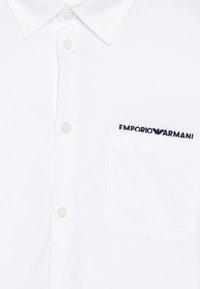 Bílá košile s krátkým rukávem vyrobená z bavlny, s límečkem na knoflíky, předními knoflíky a náprsní kapsou s vyšitým logem "Emporio Armani".