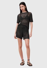 Zwart gebreid twee-delig outfit met een T-shirt met korte mouwen en een gaaspatroon, en bijpassende shorts met een elastische tailleband en koord.