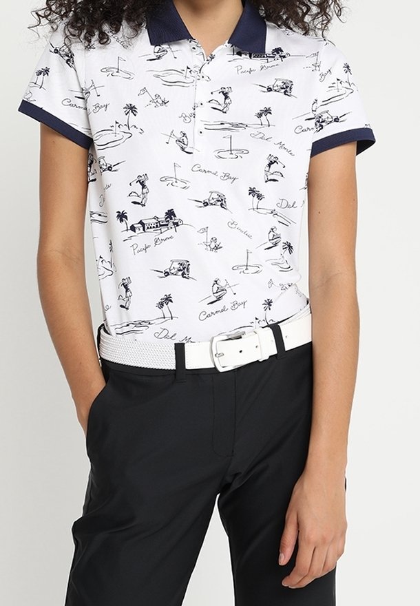 Polo blanc avec col et poignets bleu marine, présentant un motif de scènes de golf et de plage. Associé à un pantalon noir et une ceinture blanche.