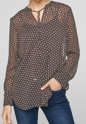 Transparente schwarze Bluse mit einem gemusterten Design, das rote und weiße Formen zeigt, einem Krawattenhals und Knopfakzenten an der Vorderseite.