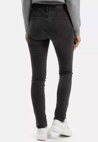 Szare dżinsowe skinny jeansy z tylnymi kieszeniami, wysoki stan i miękka tekstura, w połączeniu z białymi sneakersami.