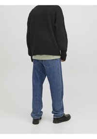 Czarny sweter z dzianiny, o luźnym kroju, w połączeniu z niebieskimi dżinsami. Gładka faktura, jednolity wzór oraz czarne buty dopełniają stylizację.