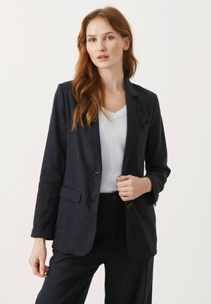 Navy linen blazer with a single-button closure, notch lapels, and two front pockets; paired with a white t-shirt and matching trousers.