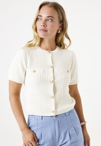 Weißer, kurzärmeliger Cardigan mit strukturiertem, geripptem Design, runder Ausschnitt, vorderem Knopfverschluss und zwei Brusttaschen.