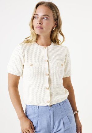 White, short-sleeve cardigan with a textured, ribbed design, featuring a round neckline, front buttons, and two chest pockets.