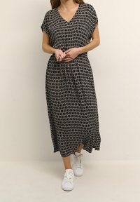 Vestido maxi de estampado en blanco y negro con escote en V, mangas cortas y corte relajado. Combinado con zapatillas blancas para un look casual.