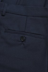 Mörkblå tygbyxor med en enda bakficka med svart knappstängning. Slät textur med en skräddarsydd design.