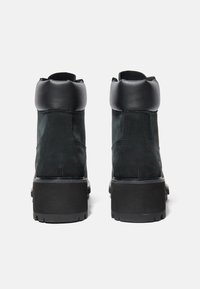 Svarta läderankelboots med rundad topp, med en tjock svart sula och sömnad detaljer på sidorna.