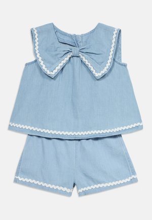 Ensemble sans manches bleu clair pour tout-petit avec grand col nœud et bordure blanche ondulée sur le haut et le short.