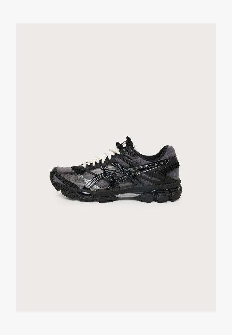 Μαύρο και γκρι παπούτσι τρεξίματος Asics με λευκά κορδόνια, εμφανισμένο από το πλάι σε απλό ανοιχτό φόντο.