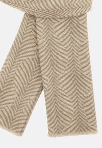 Beige tørklæde med et fiskebensmønster, lavet af et blødt, tekstureret materiale. Uferdige frynser fremhæver designet.