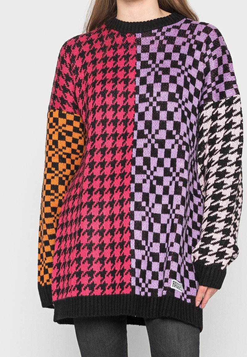 Bunter gestrickter Pullover mit einem markanten Schachbrettmuster in Pink, Orange, Schwarz und Lila, ausgestattet mit einem schwarzen, gerippten Rundhalsausschnitt und Bündchen.