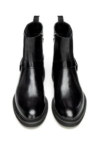 Botines de cuero negro con un diseño elegante, textura suave, cremalleras laterales y detalles de costuras contrastantes a lo largo de la suela.