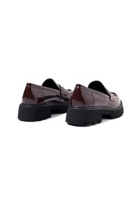 Scarpe in pelle verniciata bordeaux con suola nera spessa; caratterizzate da una finitura liscia e un design senza lacci con dettagli di cucitura minimi.