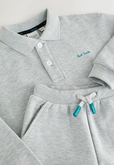 Pilka medvilninė polo marškinėliai su trimis mygtukais ir išsiuvinėtu "Paul Smith" logotipu teal spalvos; derinami su atitinkančiomis pilkomis sportinėmis kelnėmis su paleidimo raišteliu ir raukšlėmis.