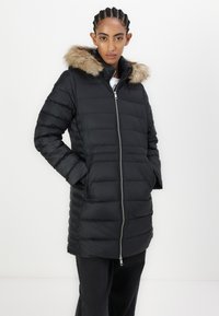 Crna puffer jakna s kapuljačom od umjetnog krzna, s horizontalnim prešanim dizajnom, zatvaranjem na zip i bočnim džepovima. Glatka tekstura, silueta do koljena.