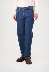 Blauwe denim jeans met een rechte pasvorm, voorzien van riemlussen, vijf zakken en een knoopsluiting. Draag ze met bordeauxkleurige loafers.