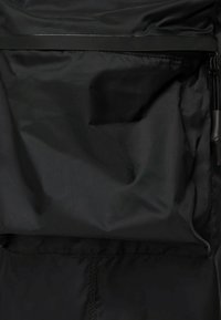 Svart nylontyg med matt yta, med en dragkedjeficka och en slät textur. Enkel, funktionell design utan synliga mönster.