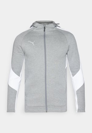 Grå zip-up jakke lavet af blødt stof, med hvide sidepaneler, en hætte og et lille logo på brystet. Glat tekstur, atletisk pasform.