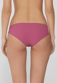 El bikini de color magenta presenta una textura suave, un diseño de tiro bajo y un corte minimalista, adecuado para trajes de baño. Sin patrones ni herrajes destacados.