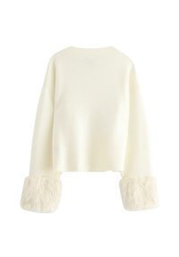 Cremefarvet langærmet trøje med brede manchetter, der har fluffy faux fur kant, vist mod en hvid baggrund.