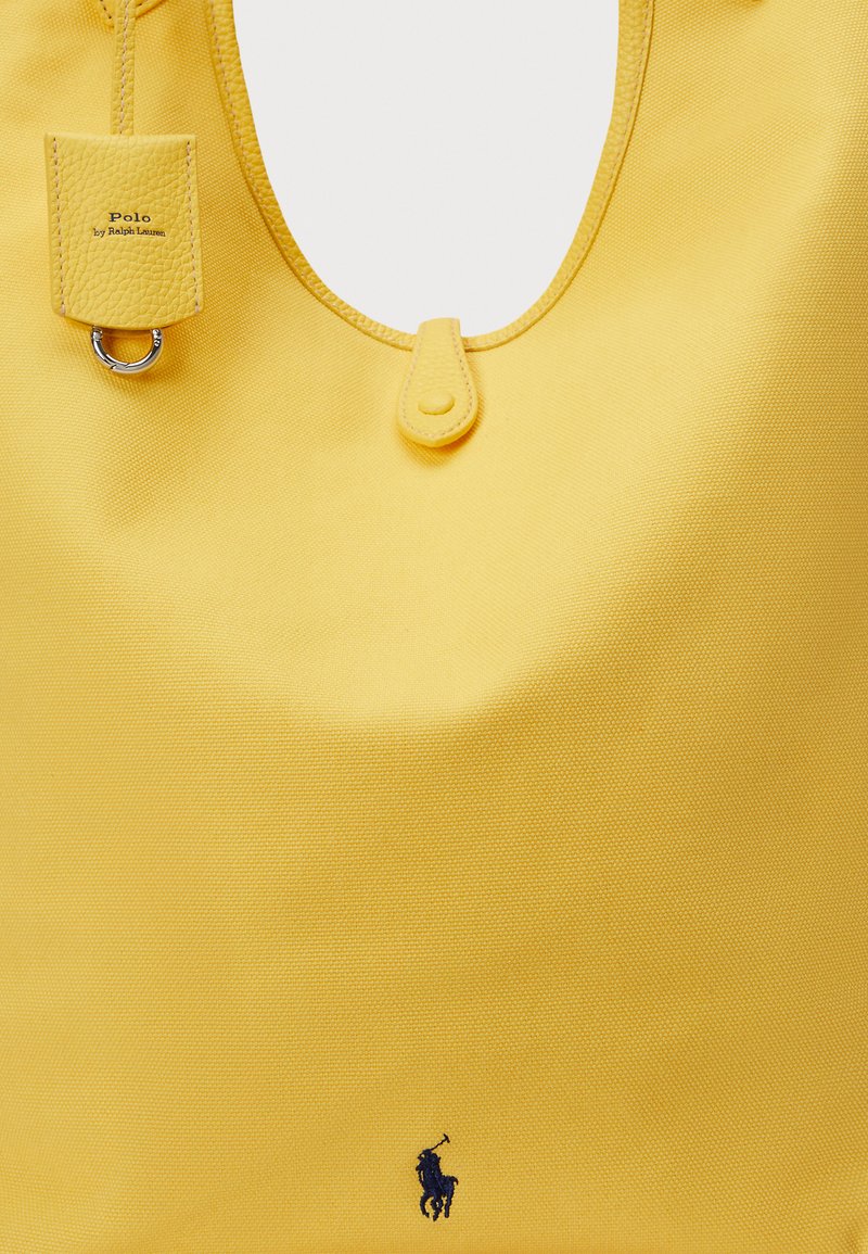 Yellow bag made of textured fabric, featuring a rounded shape, leather accents, a tag with "Polo by Ralph Lauren," and a logo in navy.