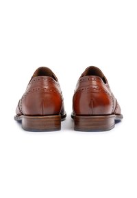Scarpe eleganti in pelle marrone con design a punta d'aquila, caratterizzate da dettagli brogue, una punta arrotondata e un tacco impilato in legno.