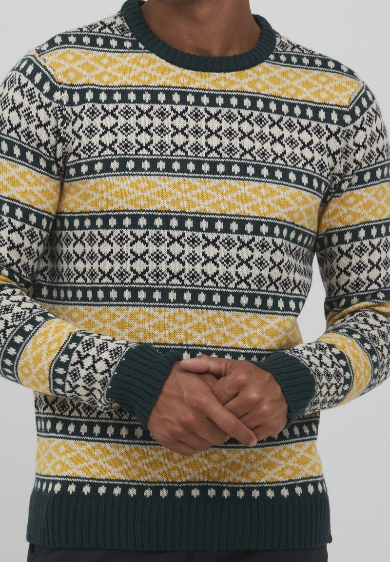 Strickpullover mit einem Fair-Isle-Muster in Creme, Senfgelb, Dunkelgrün und Schwarz. Ribbelbündchen und Saum. Klassisches Rundhalsdesign.