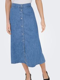 Jupe midi en jean bleu avec bouton sur le devant, portée avec un haut blanc et des chaussures noires, visible de la taille jusqu'au milieu du mollet.