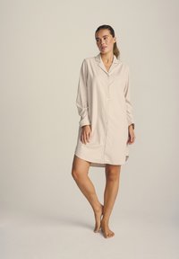 Camicia da notte a strisce color beige chiaro, maniche lunghe, abbottonatura frontale, taschino sul petto, tessuto morbido, vestibilità ampia, lunghezza fino al ginocchio.