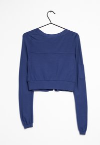 Crop top i mörkblå bomull, med långa ärmar, rund halsringning och en ficka med lock på vänster ärm. Slät textur, minimalistisk design.