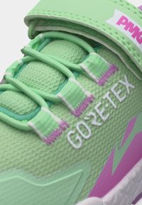 Πράσινο και μωβ αθλητικό παπούτσι με λογότυπο Gore-Tex σε λεπτό ύφασμα δίχτυ και ελαστικά κορδόνια με ραμμένες ετικέτες κοντά στη γλώσσα.