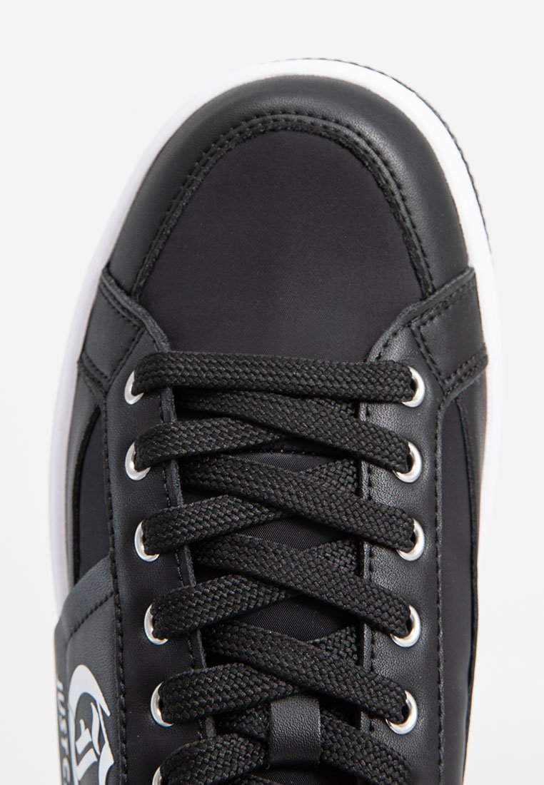 Czarne sneakersy z gładkiej skórzanej cholewki, okrągłym nosku, zamkniętym systemem sznurowania, metalowymi oczkami i białą gumową podeszwą.