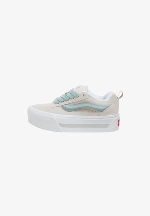 Zapatilla baja beige con suela plataforma blanca gruesa, franja lateral azul claro y cordones azul claro a juego.