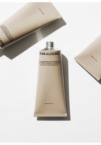 75ml tube van beige gezichtsmasker met zilveren metalen dop. Tekst bevat "Crown Alchemist" en productdetails in zwarte lettertype. Soepele, matte afwerking.