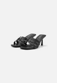 Sandale negre cu tocuri, cu mai multe bretele late și un design elegant. Au un vârf pătrat și un toc subțire stil stiletto. Textură din piele netedă.