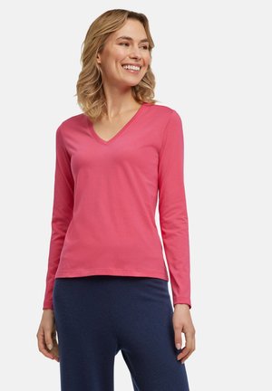 Langsleeve, V-hals shirt van felroze zacht katoen. Heeft een relaxte pasvorm en een gladde textuur, aangevuld met marineblauwe broeken.