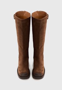 Brown suede knee-high boots with a smooth texture, flat brown sole, and a silver-tone adjustable buckle on the side.