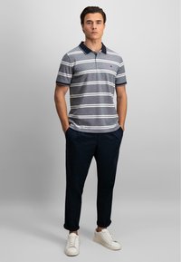 Stripet polo skjorte i grå, hvit og marineblå, med marineblå krage. Kombinert med marineblå bukser og hvite sneakers. Casuall passform, korte ermer.