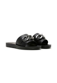 Chanclas negras con bandas anchas, que presentan un acento de cadena metálica en la parte frontal. Fabricadas con material sintético suave y suela plana.