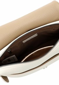 Lederhandtasche mit beigem Außenmaterial und weißem Boden. Das Innere verfügt über eine braune Stoffauskleidung, einen Reißverschluss und mehrere Fächer.