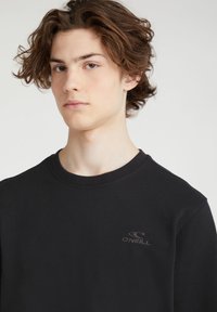 Sudadera negra con cuello redondo, tejido texturizado y un pequeño logo bordado de O'Neill en el pecho.