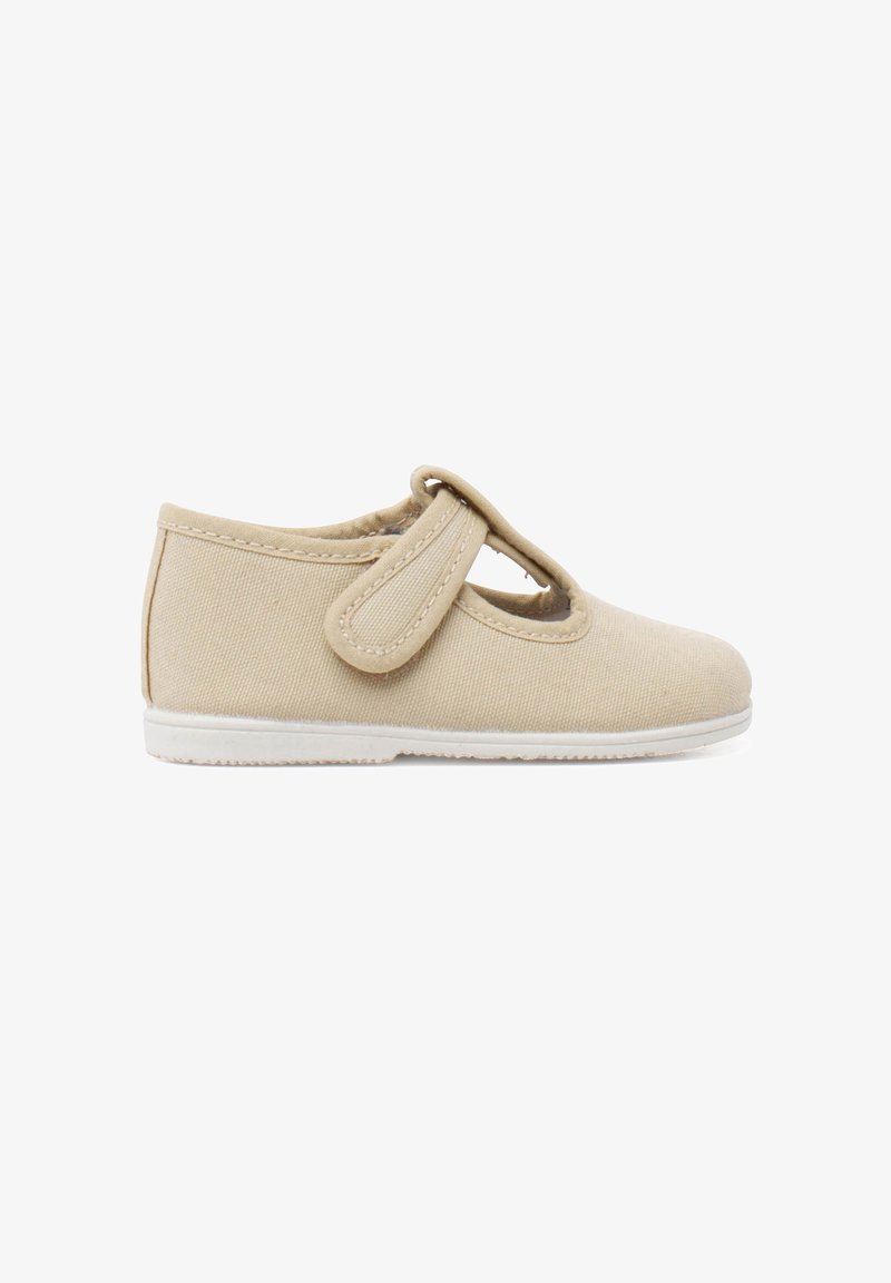 Chaussure en toile beige avec un bout rond, une sangle Velcro et une semelle en caoutchouc blanc. La tige présente un tissu texturé avec une finition lisse.