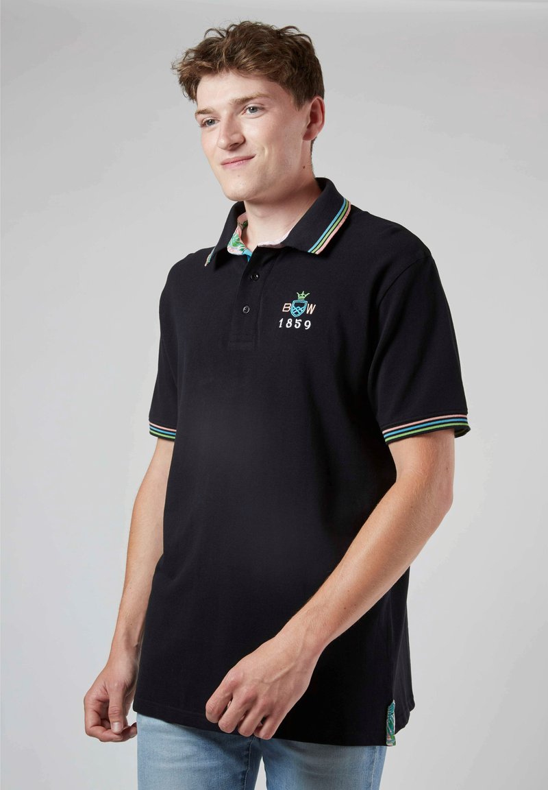 Polo shirt noir avec col rayé coloré, avec logo brodé et l'année "1859". Fabriqué en matériau en coton doux, coupe décontractée.
