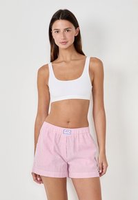 Witte geribbelde crop top gecombineerd met roze en witte gestreepte pyjamashorts met een elastische tailleband en een klein logo-opdruk.