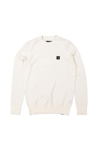 Pull en tricot blanc avec un motif texturé, col rond et poignets côtelés, arborant une petite patch logo noire sur la poitrine.